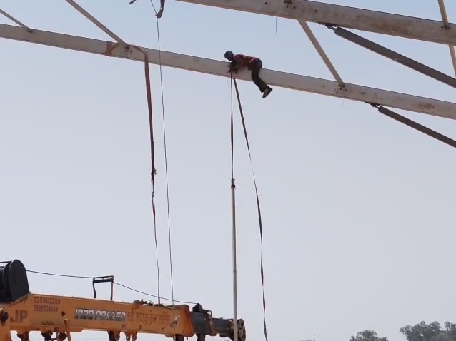 जेसीबी की मदद से पाइप पर चढ़कर पंडाल लगाते हुए।