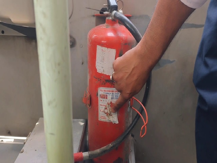 स्कूल बस के अंदर लगे फायर सिलेंडर की पर्ची दिखाता कर्मचारी।