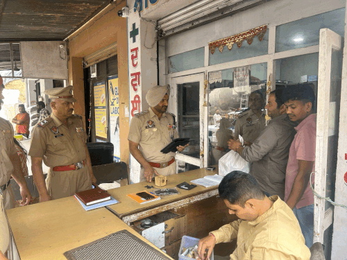 दवाओं की दुकान में रिकॉर्ड चेक करते हुए पुलिस अधिकारी।