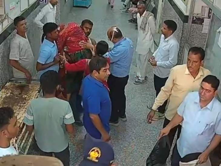 पत्नी का शव कंधे पर डाले पति को समझाइश करते अस्पताल कर्मचारी।