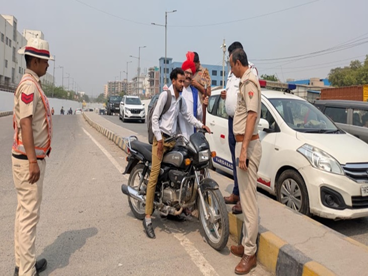 फरीदाबाद में दो पहिया वाहन चालक को रोकते हुए पुलिस कर्मचारी।