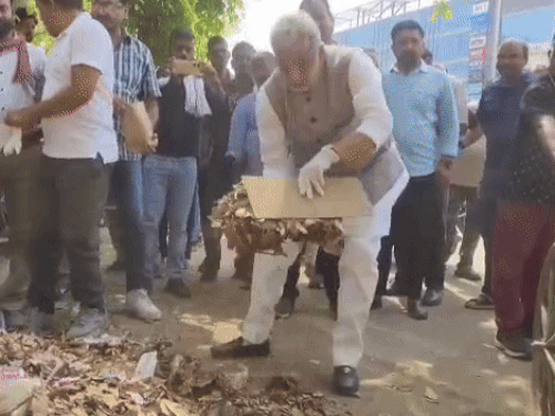 कूड़ा उठाकर रिक्शा में डालते हुए मंत्री कृष्णपाल गुर्जर