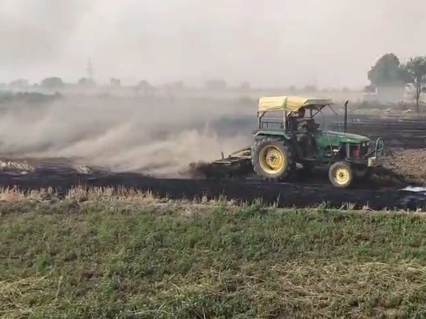 ट्रैक्टर से आग बुझाने की कोशिश करता किसान।