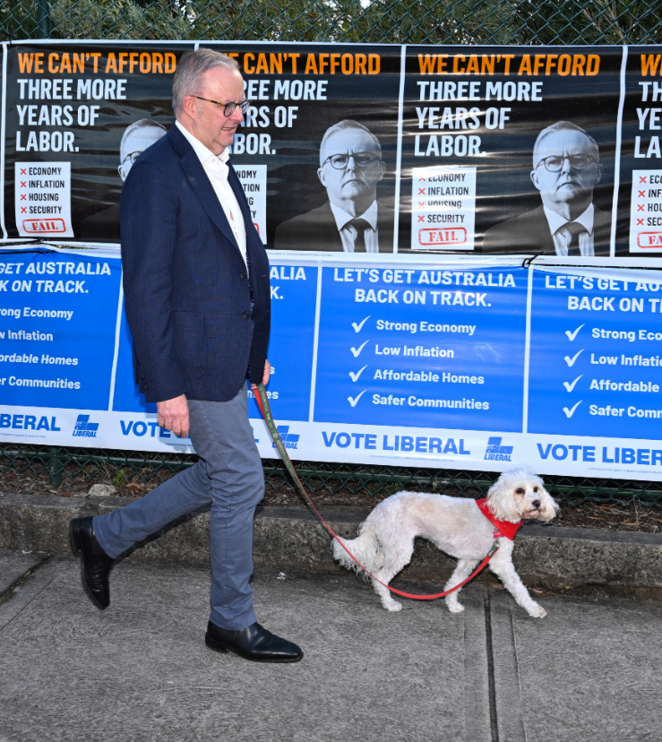 ऑस्ट्रेलियाई पीएम वोट देने के लिए अपने डॉग के साथ पोलिंग बूथ पर जाते हुए। बैकग्राउंड में विरोधी पार्टी का पोस्टर है। इसमें लिखा है- हम 3 साल और इस सरकार को बर्दाश्त नहीं कर सकते।