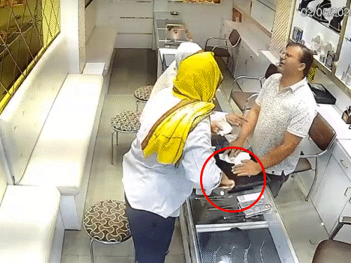 दुकानदार को बातों में उलझाकर एक साथ जेब में पाउच में रखा सोने का सेट और चेन रखते हुए और दूसरे हाथ में चांदी के सामान के रुपए देने का झांसा देते हुए।