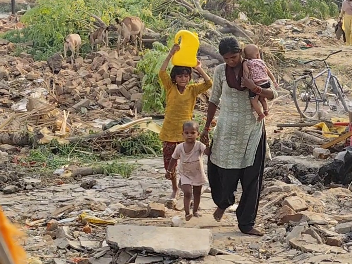 घर टूटने के बाद बच्चों को लेकर जाती महिला।