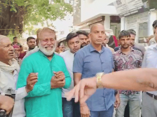 अधिकारी के कंधे पर थपकी मारते हुए डॉ. कृष्ण मिड्ढा