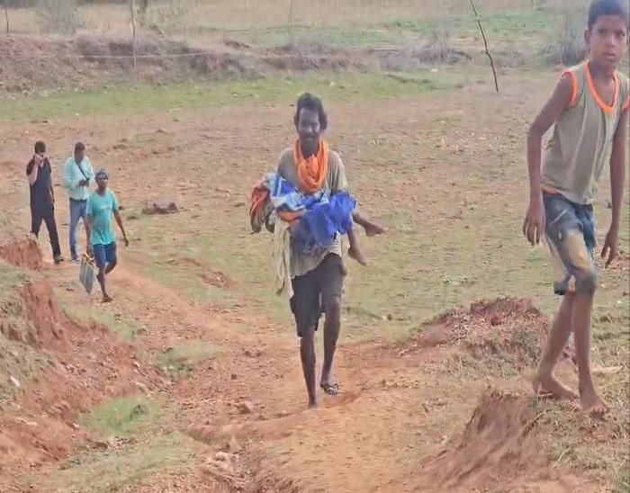 बच्चे के शव को उठाकर घर ले जाते हुए पिता, उनके साथ परिजन भी मौजूद।