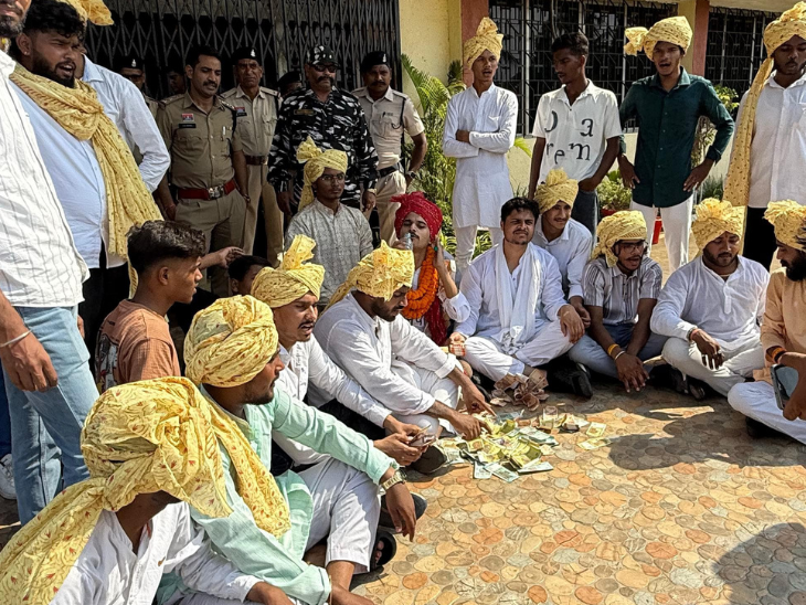 जमीन पर नकली नोटों का बंडल फैलाकर विरोध करते कार्यकर्ता।