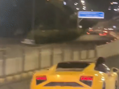 वाहनों से आगे निकलकर हाथ दिखाते हुए जाता लैंबॉर्गिनी सवार युवक।