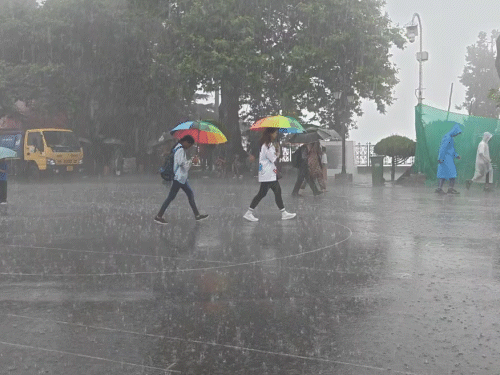 रिज पर तेज बारिश के बीच छाता लेकर चलते लोग