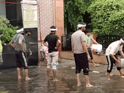 हिसार में हरियाणा एग्रीकल्चर यूनिवर्सिटी के गेट पर जमा पानी को निकालते हुए छात्र।