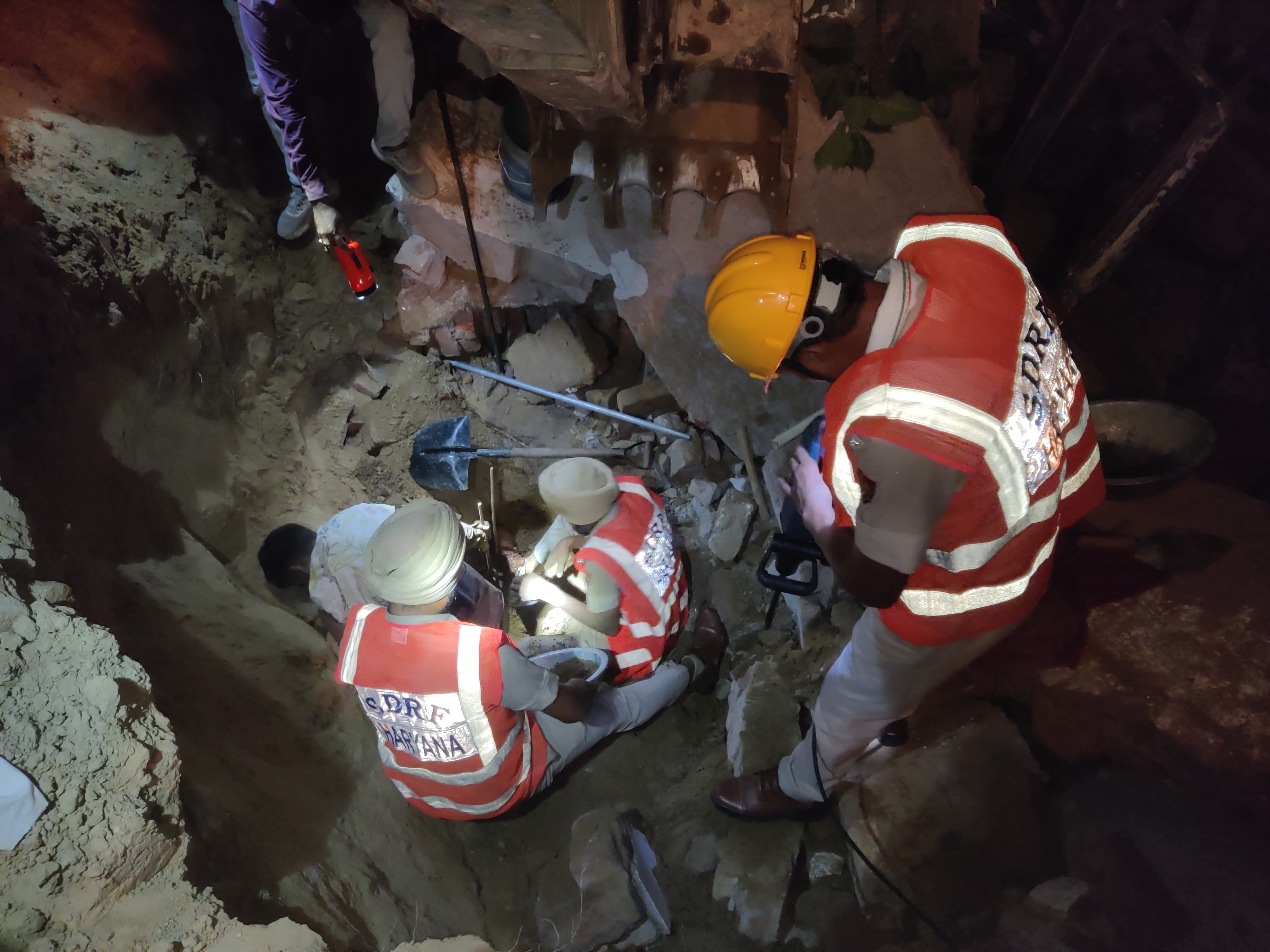 गुरुग्राम के बसई में दीवार के मलबे में दबे व्यक्ति को निकालते रेस्क्यू टीम के सदस्य।