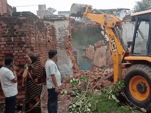 कृषक सेवा समिति के जर्जर भवन को बुलडोजर से गिराया जा रहा है।