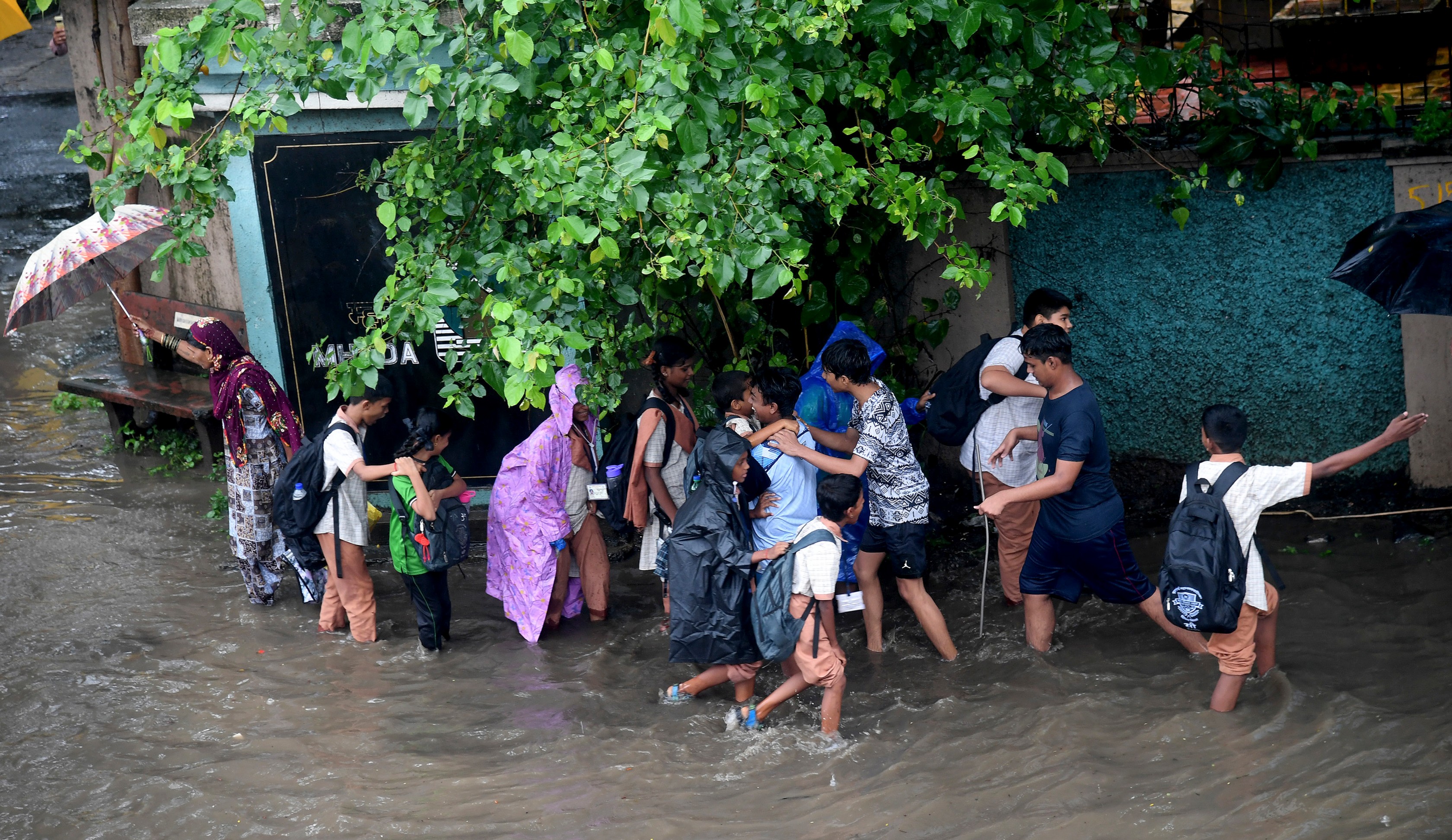 School children passing through the road filled with water after heavy rains in Mumbai.