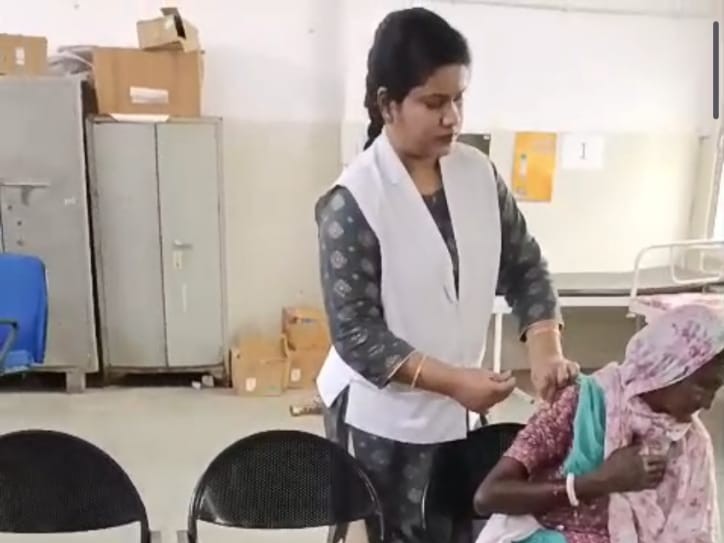 कपड़े के ऊपर से इंजेक्शन लगाती हुई नर्स।