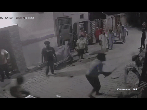 Attacker youth and policemen saving their lives by hiding in the house. The woman and her daughter are standing behind.