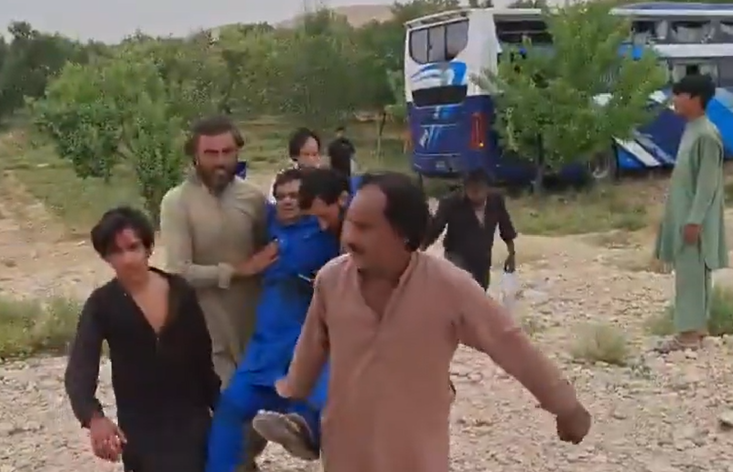 People carrying a man injured by firing at Balochistan's Yalat.