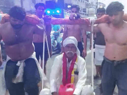 यूपी के अलीगढ़ में दो भाई अपने पिता को कावड़ के साथ कंधे पर उठाए हुए।