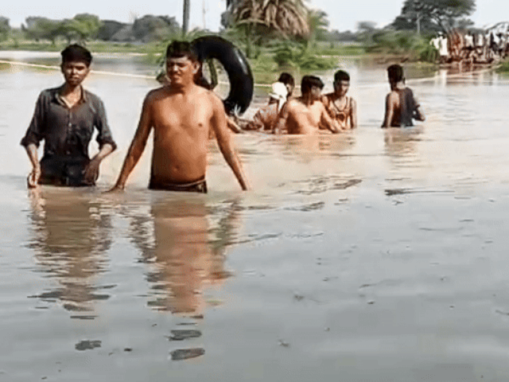 रस्सी और टायर के ट्यूब के सहारे रास्ता पार करते ग्रामीण
