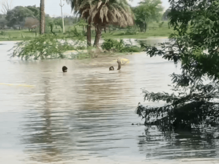 रस्सी के सहारे दरिया बन चुकी सड़क पार करते ग्रामीण