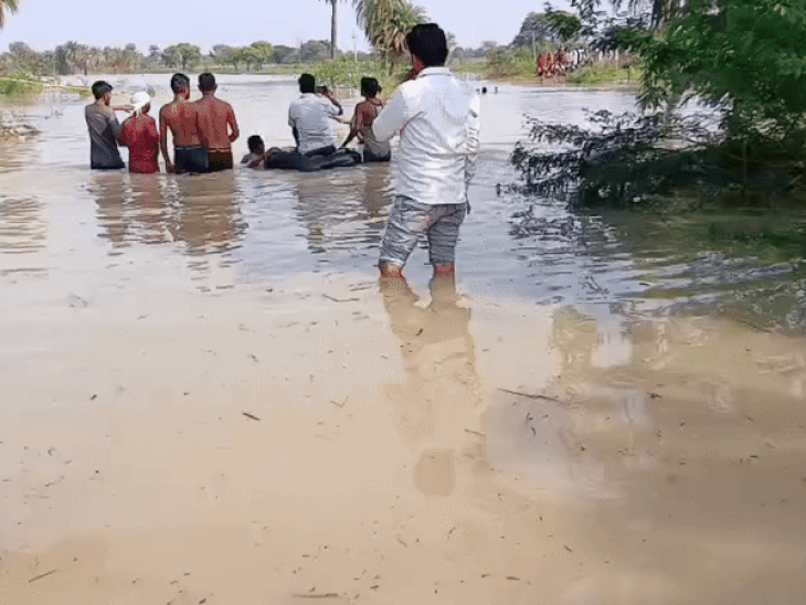 युवक को ट्यूब की बनाई नाव पर बिठाकर रास्ता पार कराते ग्रामीण