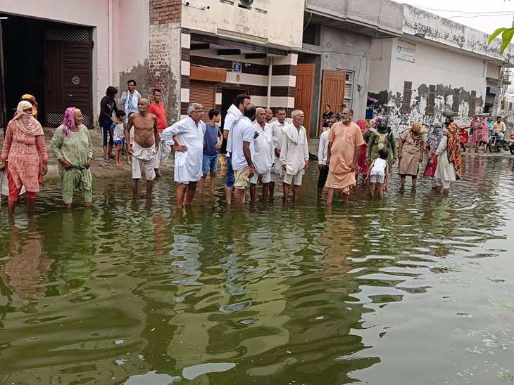 गांव पुर के ग्रामीण गांव में हुए जलभराव में खड़े होकर रोष जताते हुए