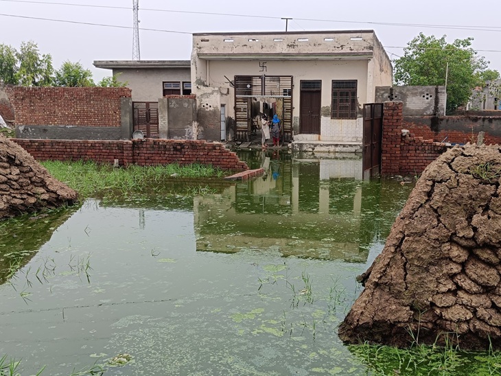 गांव पुर में जलभराव व घर के बाहर खड़ी महिलाएं, जिनके घर से निकलने का रास्ता भी नहीं है