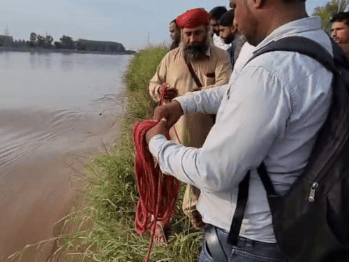 रस्सी के जरिए शव को बाहर निकालते गोताखोर।