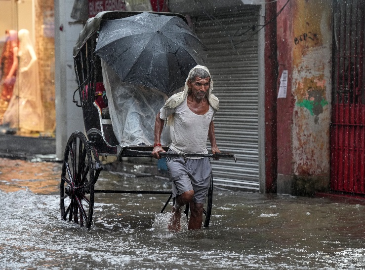 कोलकाता में पिछले 24 घंटों से हो रही बारिश से सड़कें लबालब भर गई हैं। इसी सड़क से इक्का गाड़ी निकालता एक चालक।