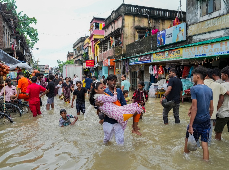 कोलकाता में 24 घंटे से हो रही बारिश के कारण गंगा ऊफान पर है। सड़क पर भरे पानी के बीच एक शख्य ने पत्नी को गोद में उठाकर सुरक्षित जगह पहुंचाया।