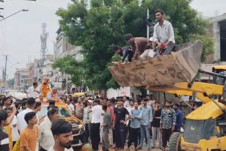 जेसीबी में बैठकर एनएसयूआई जिलाध्यक्ष पर फूल बरसाते हुए कार्यकर्ता।