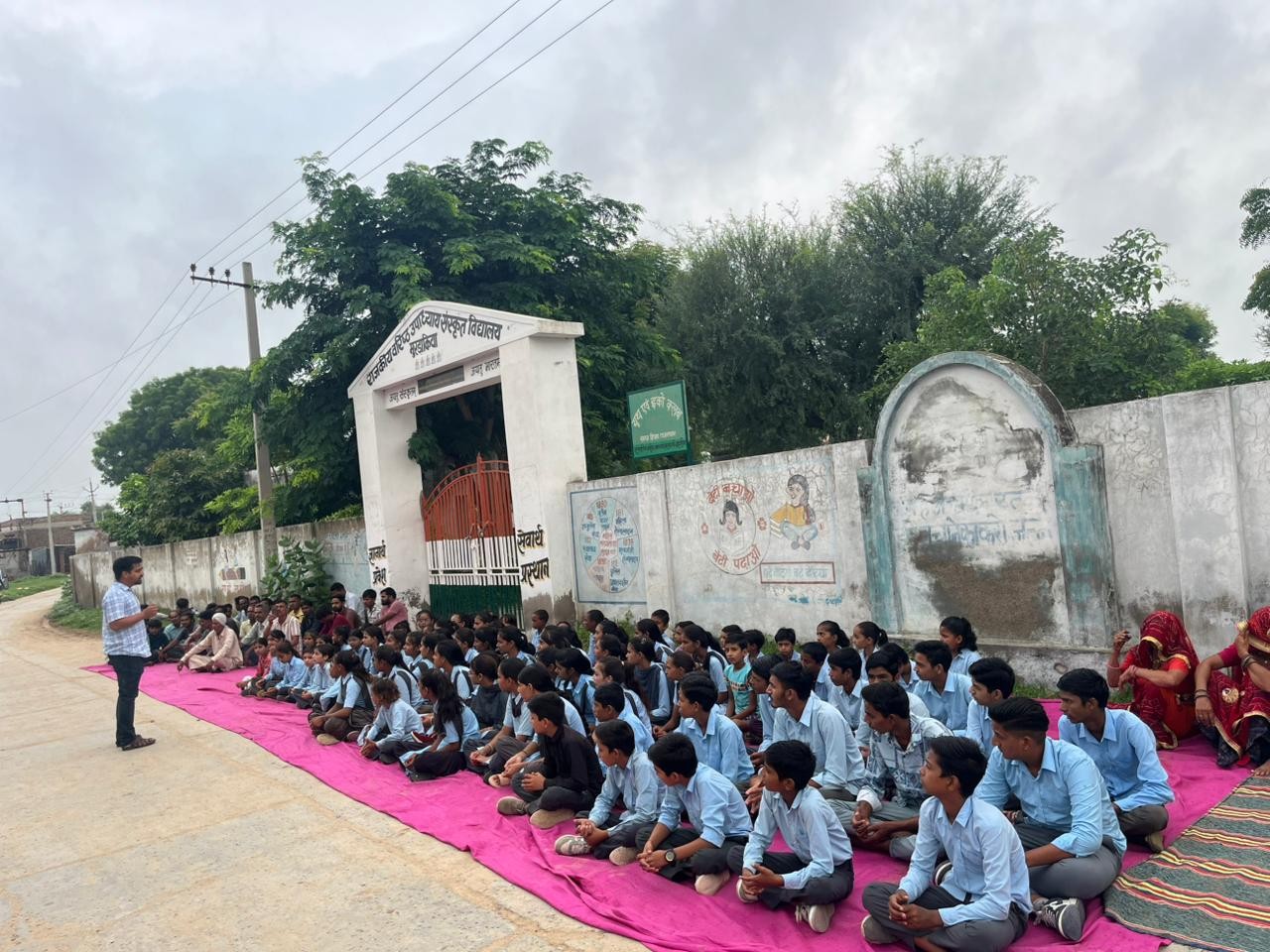 स्कूल के बाहर दरी बिछा कर बैठे स्टूडेंट।