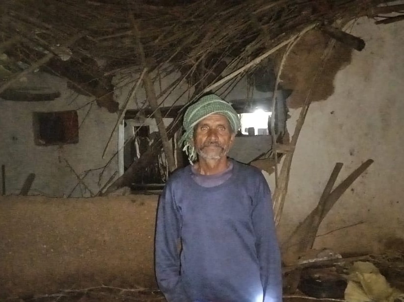 अपने क्षतिग्रस्त घर पर पास खड़ा ग्रामीण।