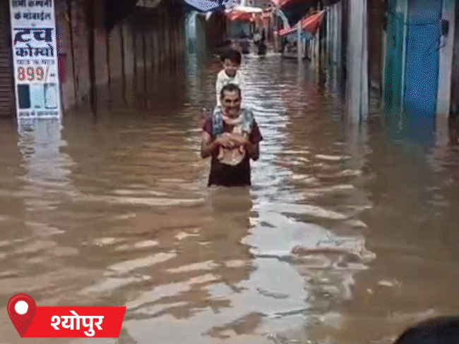 श्योपुर में सड़क पर कमर तक पानी भरे होने से एक व्यक्ति बच्चे को कंधे पर ले जाता दिखा।