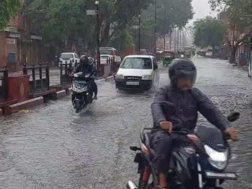 जयपुर के परकोटे में तेज बारिश के कारण सड़कों पर पानी भर गया। लोग रेनकोट पहनकर काम पर जाते नजर आए।