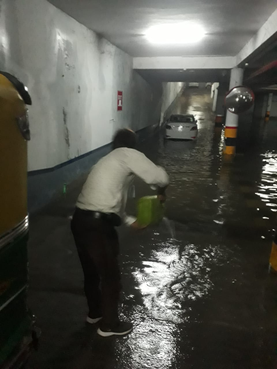 शहर एक बिल्डिंग के बेसमेंट में भरे पानी में छिड़काव करते स्वास्थ्यकर्मी।