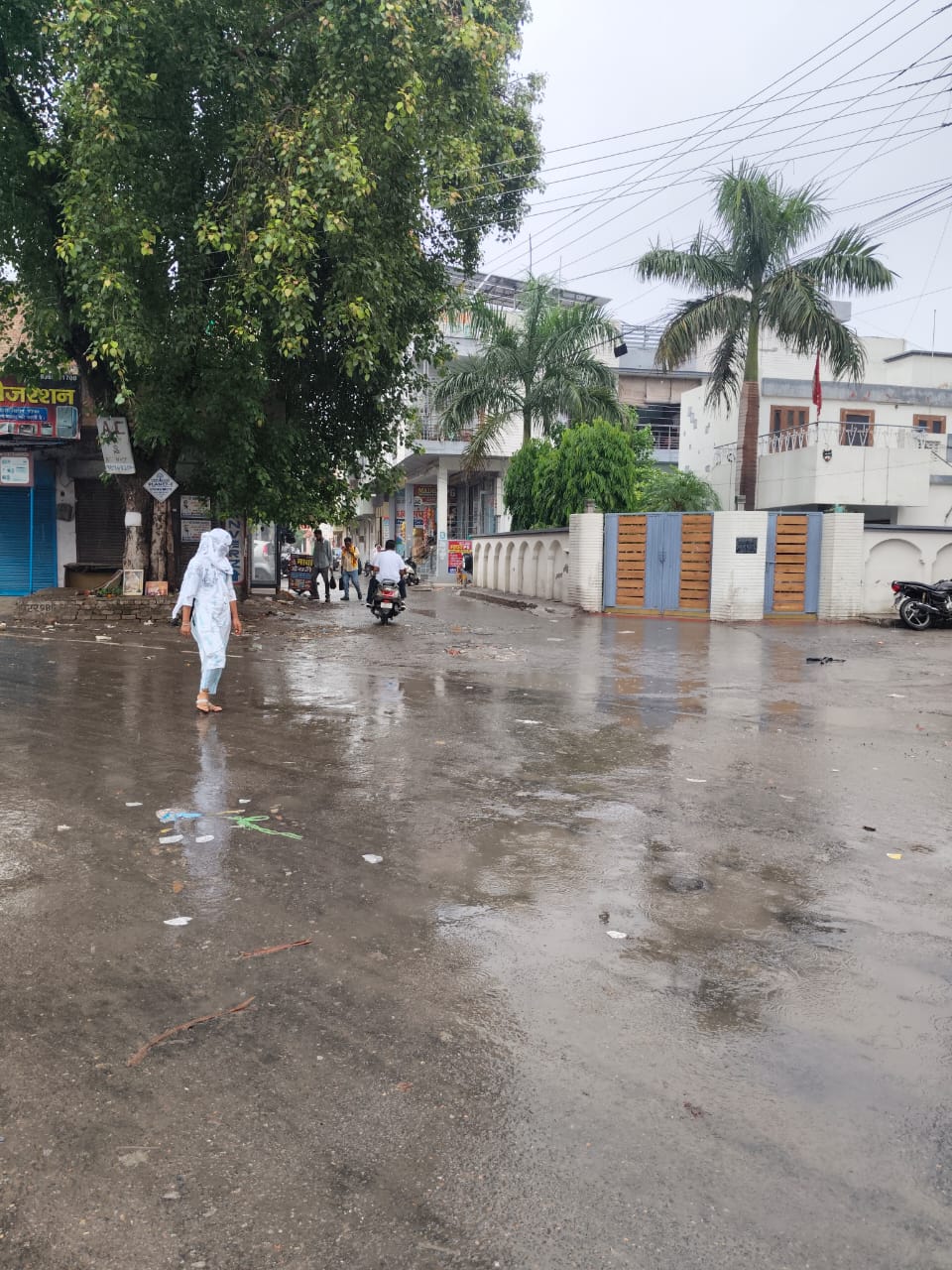पुल की ओर जाने वाले रोड पर बारिश से गुजरती युवती, दुपट्टे का सहारा लिए।