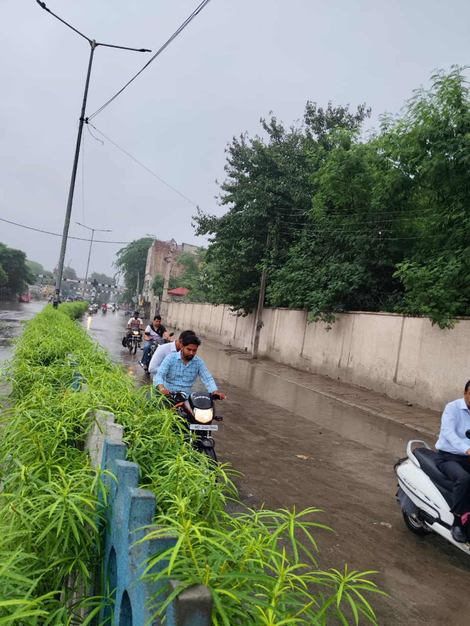 रेलवे फाटक रोड पर बारिश के चलते गुजरते वाहन चालक।