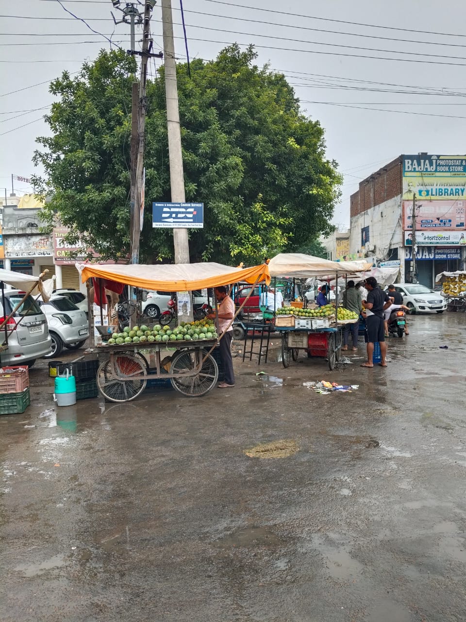 जाट धर्मशाला के पास रोड पर बारिश के चलते रेहड़ी वालों ने लगाए तिरपाल।