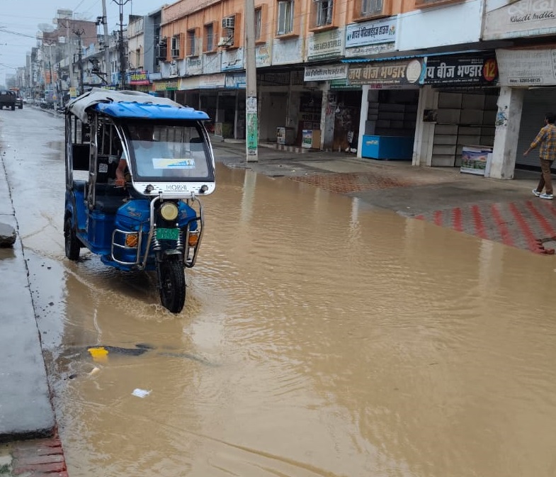रोड पर जलभराव से गुजरता ई-रिक्शा चालक।