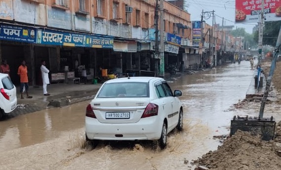 जनता भवन रोड के हालात, पानी से गुजरती गाड़ी।