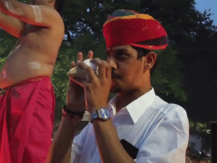 आरती के दौरान शंख बजाता एक युवा
