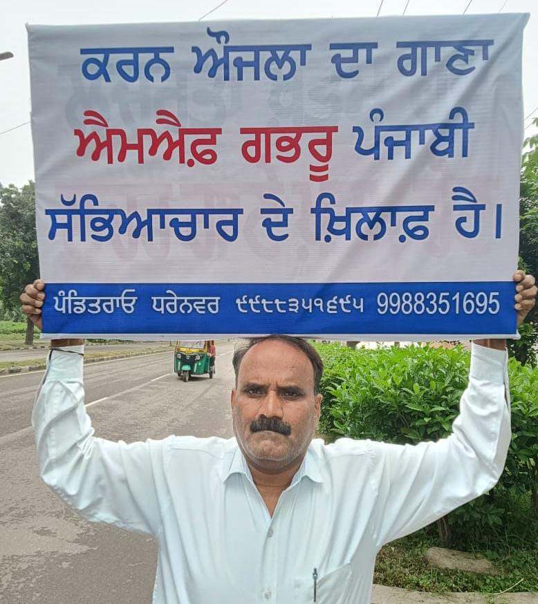 पंजाबी गायक करण औजला यांच्या विरोधात पोस्टर्स घेऊन लोकांमध्ये जागरूकता निर्माण करणारे कार्यकर्ते.