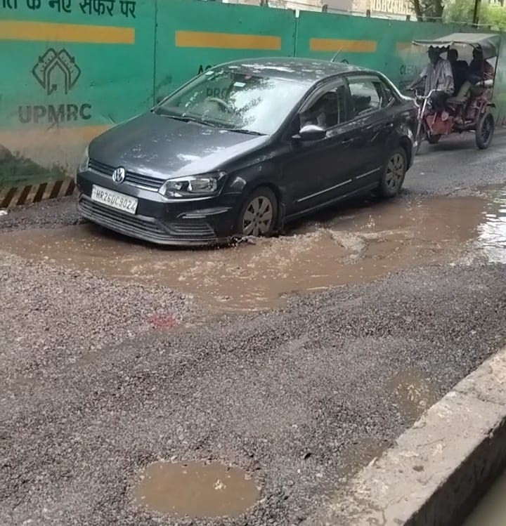 गड्ढे में हो कर निकलती कार