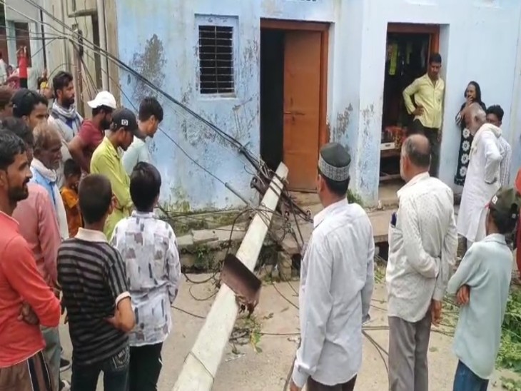 दुर्घटना के बाद मौके पर गिरा पड़ा पोल और वहां खड़े लोग।