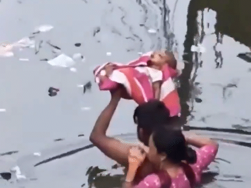 प्रयागराज में सोमवार को घरों और सड़कों पर पानी भर गया है, इस दौरान बच्चे को गोदी में लेकर बचाते माता-पिता।