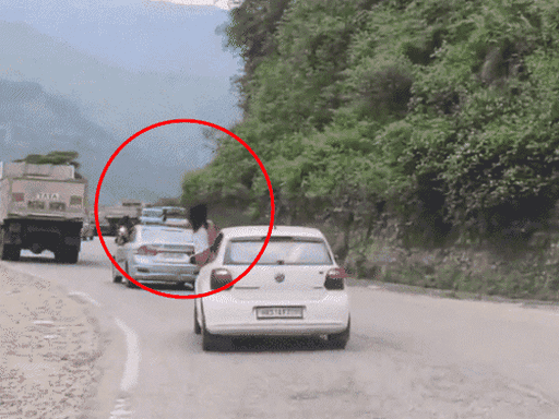 उत्तराखंड के रुद्रप्रयाग में कार की खिड़की से बाहर निकलकर वीडियो बनाती महिला।