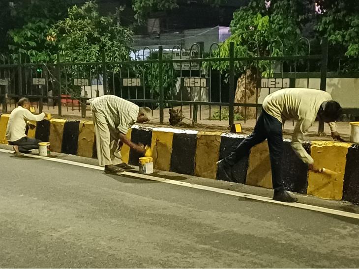 ऊर्जा भवन वाली रोड पर रात में डिवाइडर पर पेंट करते कर्मचारी।