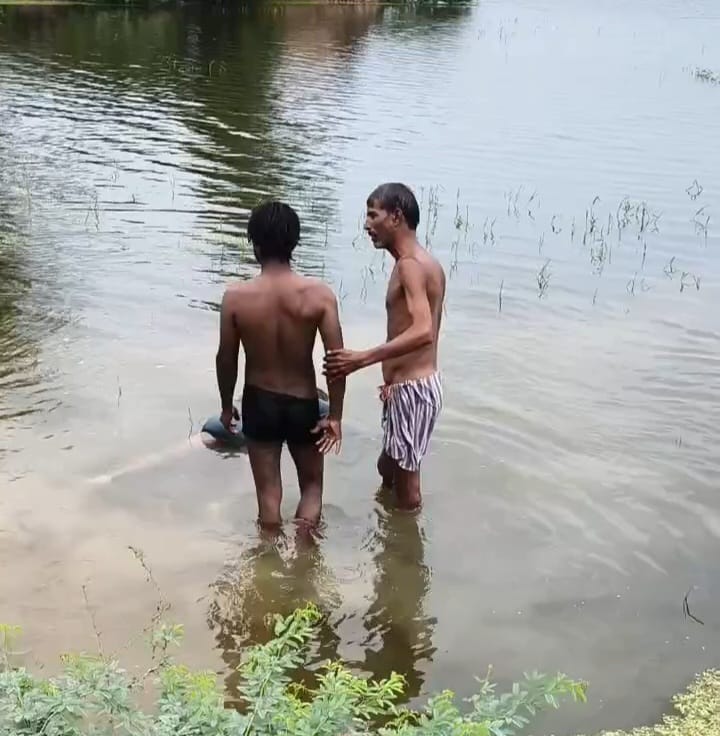 शव को पानी से बाहर निकालते स्थानीय लोग।